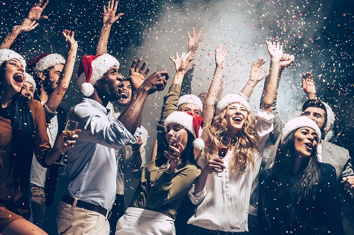 Ungdomar dansar till festmusik på en julfest, det är konfetti i luften och de har tomtemössor på sig.